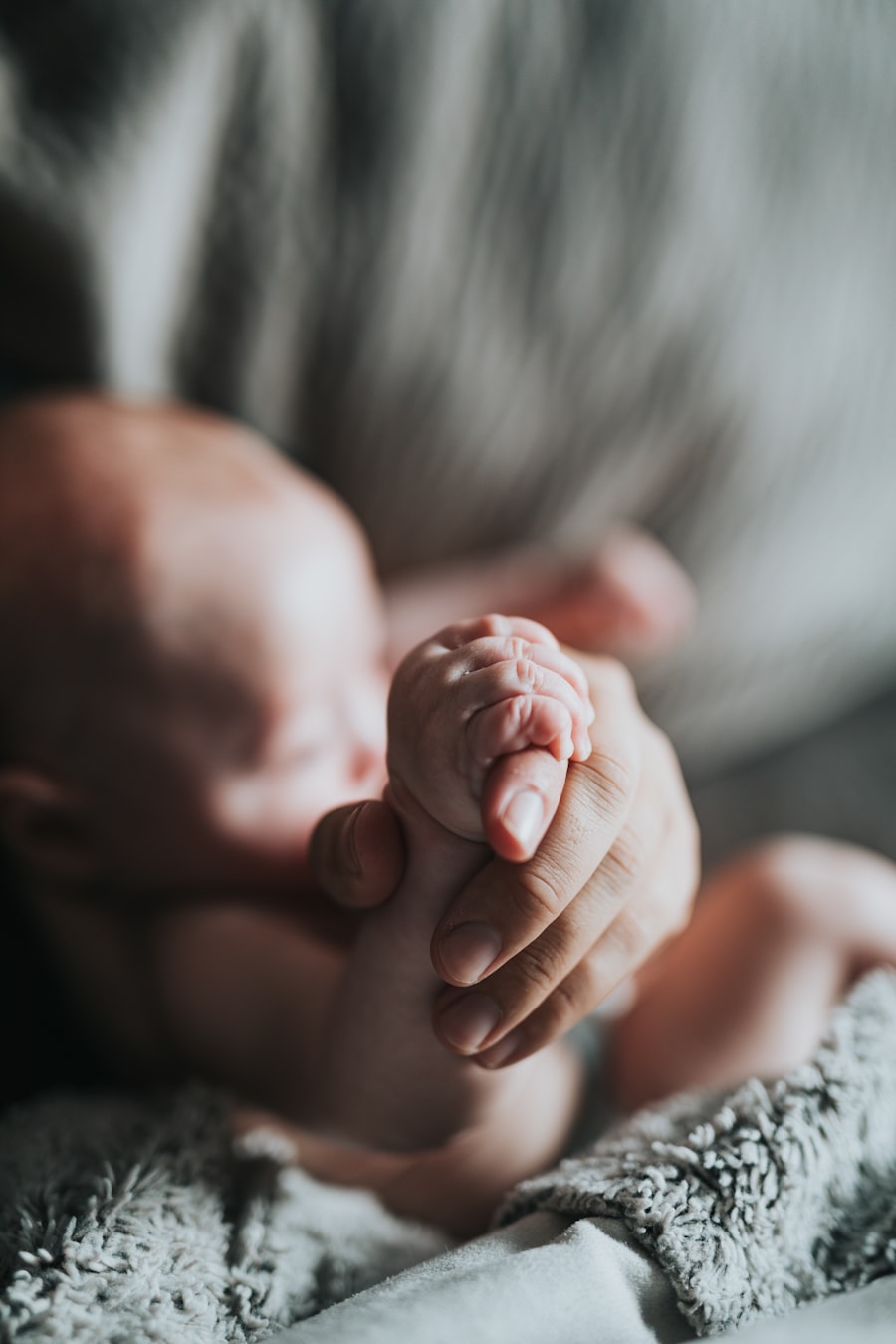 Adult hand holding tiny baby hand